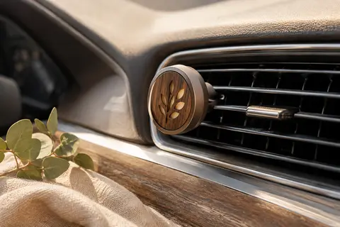 Diffuseur à clip pour voiture posé près d’une grille d’aération dans une ambiance douce et lumineuse.