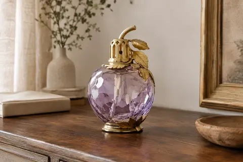 Lampe à catalyse en verre parme facetté avec monture dorée, posée sur une console en bois.