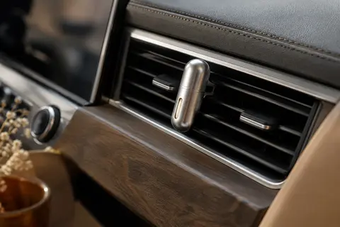Diffuseur voiture à clip argenté fixé sur une grille d’aération, avec sa recharge céramique parfumée.