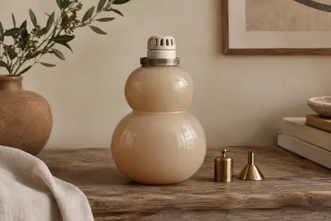 Lampe à catalyse en verre laqué nude à deux volumes arrondis, avec son brûleur sans flamme, sur une console en bois.